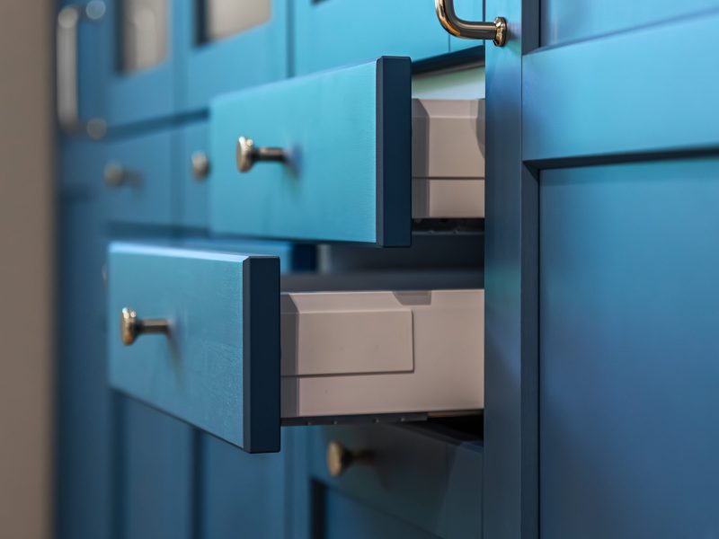 Close up of matte blue fronts with warm metal handles and clean geometry. A premium minimal aesthetic for modern interior design and organizing concepts.